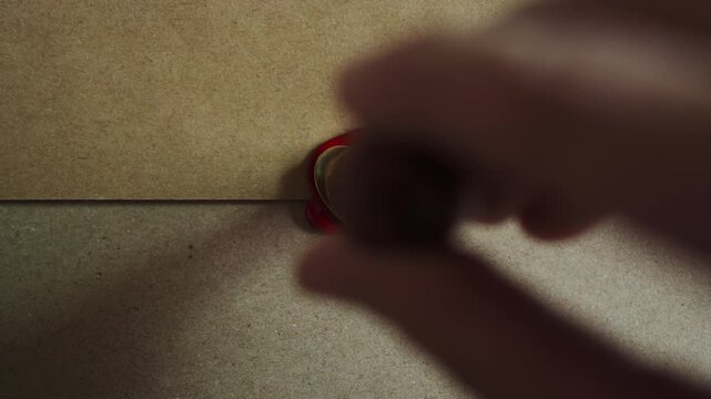 Close Up View of Stamping Heart Shape Red Wax Seal Stamp on Vintage Brown Envelope