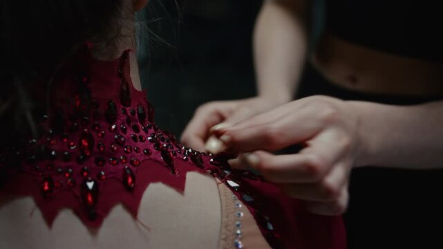 Close Up of Intricate Design, Mesh Fabric, and Brilliant Shine of Elite Competition Leotard. Reveals Dozens of Hand Stitched Rhinestones, Glittering Crystals Catching Light as Teammate Adjusts Collar.