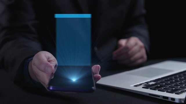 A programmer interacts with a smartphone displaying various coding languages, including HTML, Java, and Python, while using a laptop in a dark environment. Qubit