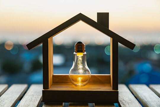 Light bulb in wooden house model real estate insurance property home loan energy saving idea mortgage refinance interest rate down payment agent investment.