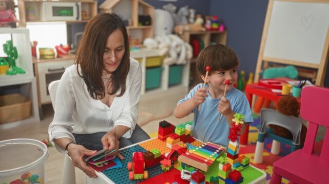 Woman shows flashcard while little boy holds mallets and plays xylophone and building blocks in a preschool building; playful learning.