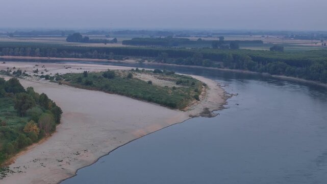 Po River reveals extensive sandbars and a vegetated island during the 2026 low water crisis near Cremona between Lombardy and Emilia-Romagna, Italy, drone pan.