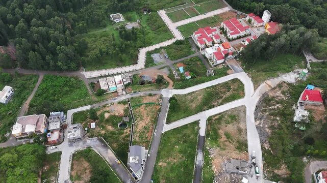 Cinematic top-down drone view of a developing residential layout in Yercaud featuring newly paved roads, plotted land, scattered homes, and lush greenery. The aerial perspective highlights planned.
