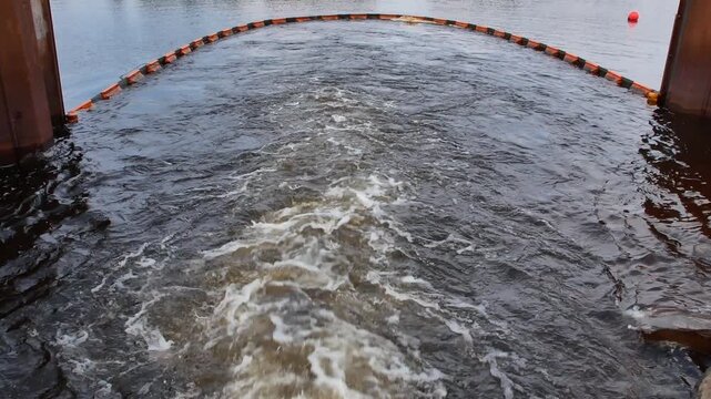 A powerful video showing thermal power plant cooling water gushing and rushing heavily into a local river or lake, creating turbulent currents