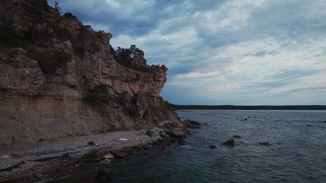 Limestone cliffs rise above the Baltic coastline at sunset in Sweden, glowing in warm light beside the calm sea and rugged shoreline.