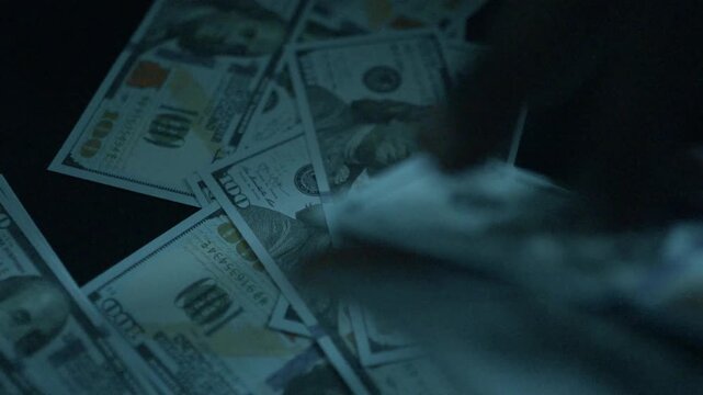A man collects scattered dollars from a table. Budget savings, bribes and corruption concept.