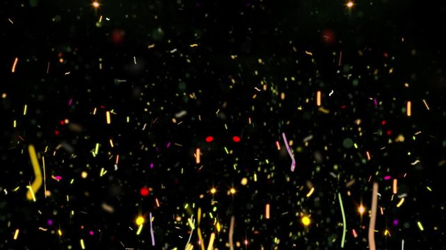 Confetti pieces fall in a dense colorful shower against a deep black background to celebrate a festive occasion or a special event.