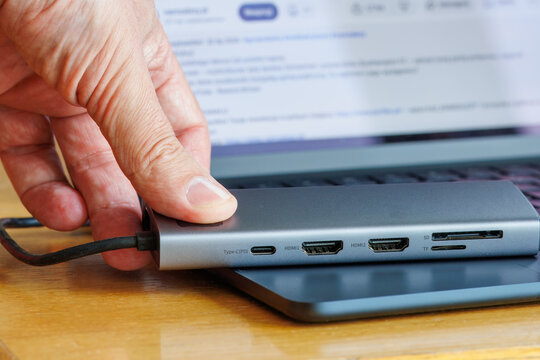 A hand holding multiport docking station adapter for computers and laptops.