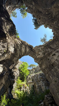 Eerie prehistoric cave abyss with sharp rock formations and a glimpse of the sky above