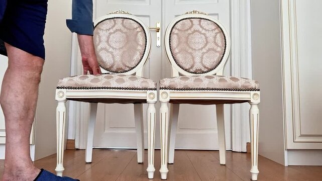 A man reaches down and picks up a smartphone left on a chair in a home setting. Natural everyday action with realistic movement, ideal for technology, communication, lifestyle, and daily routine conce