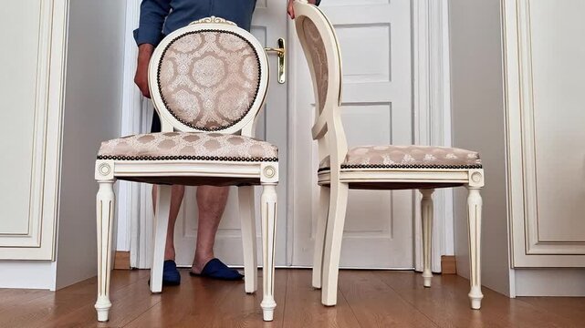 Two elegant upholstered chairs are placed side by side with smooth, deliberate movement, highlighting furniture arrangement, symmetry, soft fabric texture, craftsmanship, and everyday home styling