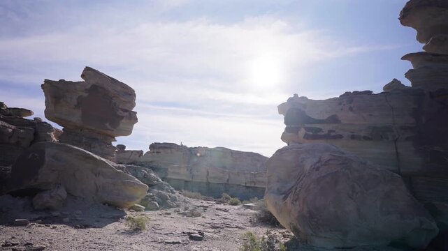 Stunning wide angle footage showcases the sunlit, rugged rock formations of Ischigualasto Provincial Park, Argentina. Striking geology and dramatic textures fill this panoramic desert scene.