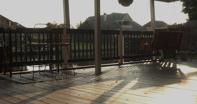 Wide cinematic footage showing empty outdoor chairs and a swinging bench facing a still Louisiana canal at dusk, creating a peaceful waterside scene in soft evening light.