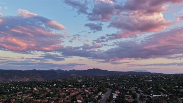 4K drone timelapse ascending over a suburban southwest town as a dynamic weather system brings stunning, changing colors to the clouds above the four corners states landscape.