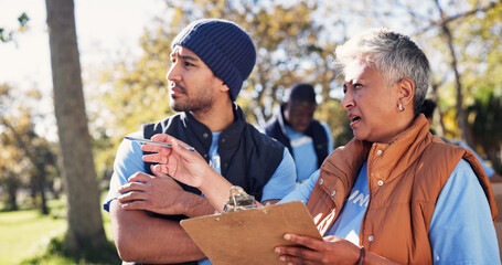 Clipboard, pointing and talking with volunteer people in park together for charity or relief work. Conversation, instructions and checklist with community team outdoor for discussion or planning © peopleimages.com