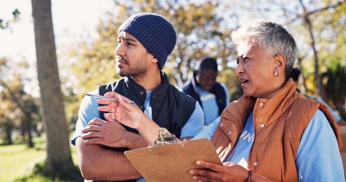 Clipboard, pointing and talking with volunteer people in park together for charity or relief work. Conversation, instructions and checklist with community team outdoor for discussion or planning