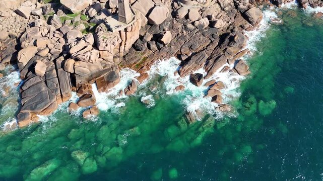 Waves crashing on Pink Granite coast Brittany France turquoise sea drone aerial view