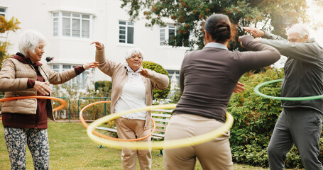 Woman, physiotherapist and hoop with senior group in garden for outdoor exercise together. Female person, fitness or instructor training with elderly people or ring for workout in retirement park © peopleimages.com