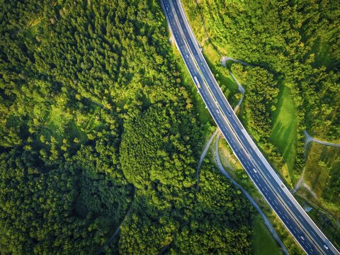Aerial dramatc view to the road with lorry and many cars and green forest around in the summer.Alps.Slovenia