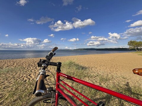 Red bicycle on sunny sandy beach under blue sky with clouds and sea in the background, Lake V&auml;ttern, J&ouml;nk&ouml;ping, Sweden