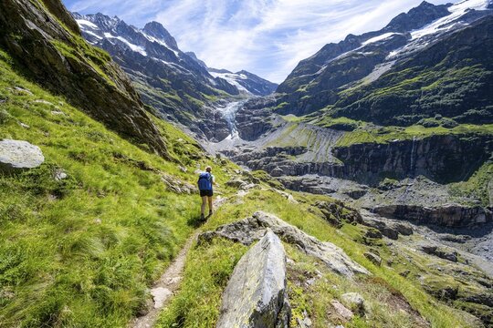 Female mountaineer hiking trail in front of mountain panorama, picturesque high-alpine mountain landscape with Lower Eismeer glacier range, hiking to Schreckhornh&uuml;tte, Bernese Oberland, Switzerland