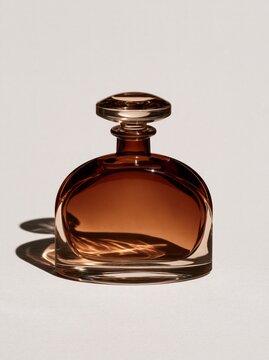Amber glass perfume bottle with round stopper on neutral background