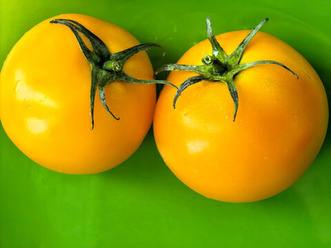 Two Fresh Yellow Tomatoes on Green Plate