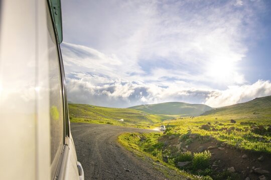White car drives on caucasian green wilderness with sky and meadow view. Tusheti. Georgia