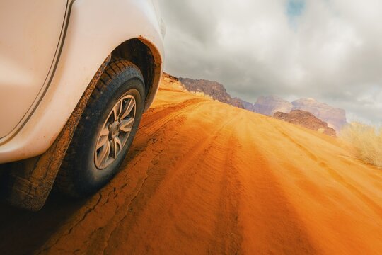 Jordan - 25th october, 2025: Close up 4wd vehicle driving across Wadi rum red sand track with desert mountains off road adventure travel. SUV driving through gravel dirt road hilly terrain landscape