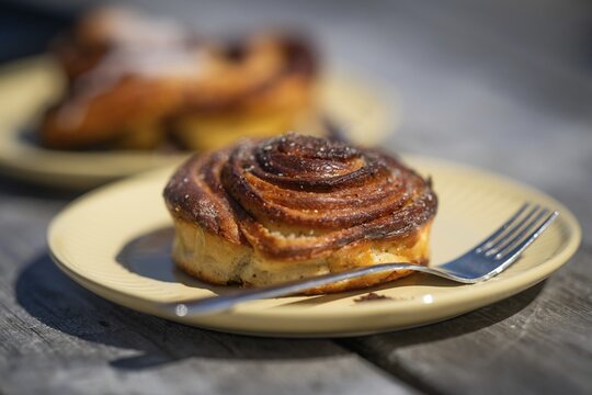 Cinnamon roll and fork lie on a light yellow plate, Houvig, Ringk&oslash;bing Fjord, Denmark