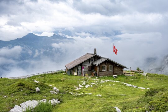 Small mountain hut Suls-Lobhornh&uuml;tte with Swiss flag, cloudy mountain landscape, Bernese Alps, Bernese Oberland, Switzerland