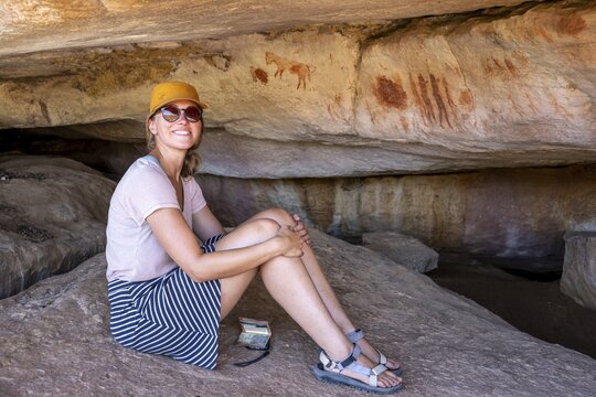 Tourist on a rock with prehistoric animal depictions, ancient rock carving of the San, indigenous people of South Africa, Seville Rock Art Trail, Cedar Mountains, Clanwilliam, Western Cape, Republic of South Africa
