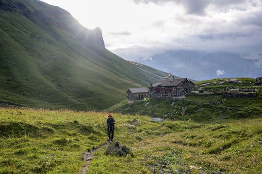 Hiker on a hiking trail, behind mountain lodge Rotstockh&uuml;tte in front of a mountain landscape, Bernese Alps, Bernese Oberland, Switzerland