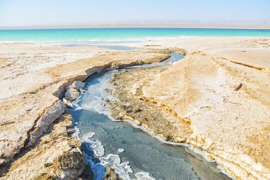 Landscape view turquoise Dead Sea water with white salt foam and ripples
