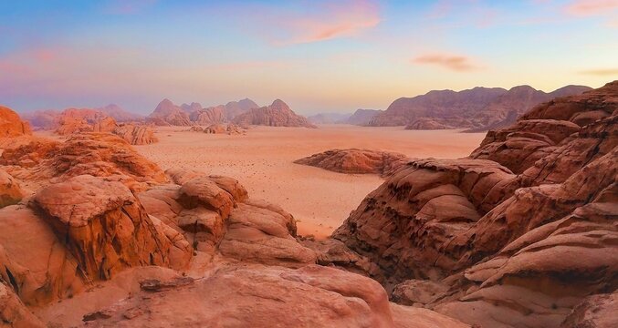 Aerial panoramic view orange Wadirum desert sand valley rock formations sandstone mountains horizon colorful pink blue twilight sunset sky wilderness landscape Wadi Rum Jordan