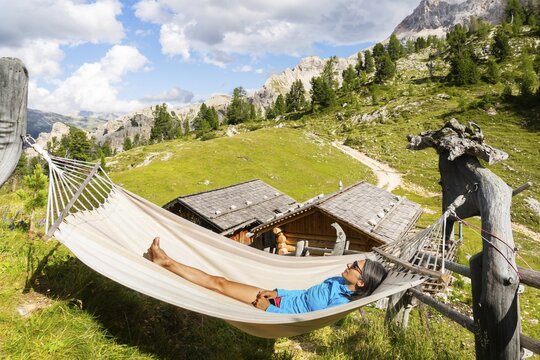 Female hiker resting in hammock at mountain hut on Tre Cime trail in Dolomites enjoying alpine scenery wellness adventure and hiking break