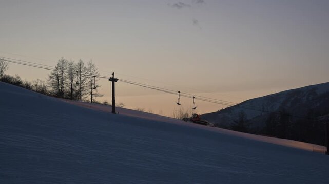 Snow Groomer Preparing a Ski Slope at Sunrise in Japan Winter Ski Resort Landscape