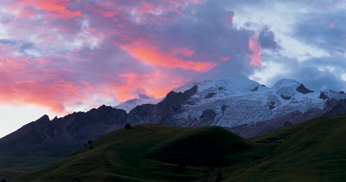 Sunset glow sky over Genie Holy Mountain, Sichuan China, colorful twilight clouds above snow-capped peaks and alpine grassland, western Sichuan plateau landscape