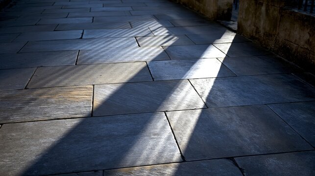 Sunlight casts dramatic shadows on stone pavement, creating a captivating visual effect.