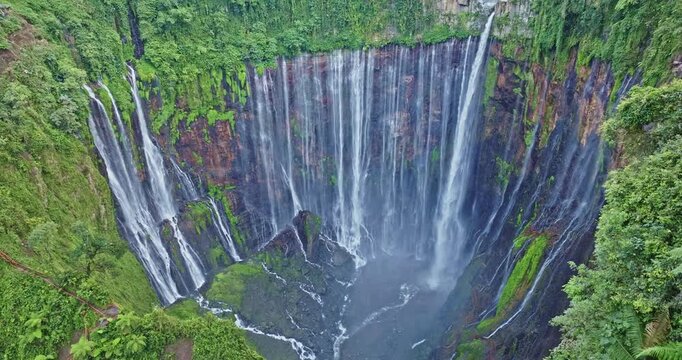 Scenic aerial photography of Indonesia's stunning Tumpak Sewu Waterfall, a world-class travel destination surrounded by lush greenery, volcanic terrain, and dramatic waterfalls.