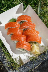 Philadelphia roll with salmon on grass. Delivery box. © Cavan