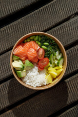 Salmon poke bowl in a delivery box on a wooden surface. Isolated © Cavan