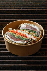 Sushi burger on a metal wire rack. Delivery box. Art photo © Cavan