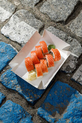 Philadelphia salmon sushi roll on road markings. Delivery box. © Cavan