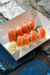 Philadelphia salmon sushi roll on road markings. Delivery box. © Cavan