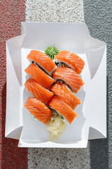 Philadelphia salmon sushi roll on road markings. Delivery box. © Cavan