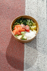 Salmon poke bowl in a delivery box on road markings. Isolated © Cavan
