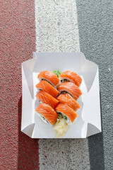 Philadelphia salmon sushi roll on road markings. Delivery box © Cavan