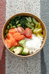 Salmon poke bowl in a delivery box on road markings. Isolated © Cavan