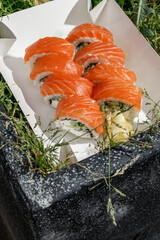 Philadelphia roll with salmon on grass. Delivery box. © Cavan